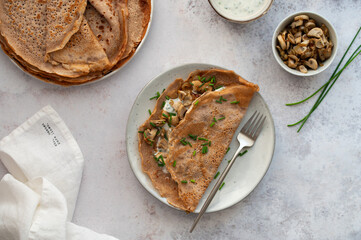 Homemade buckwheat crepes. Galettes bretonnes with mushrooms on a gray background. Traditional French cuisine.
