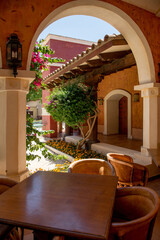 a table in a Mexican-style cafe. terracotta walk in the cafe. terracotta walls, an arch, flowers and a table in the cafe. Spanish architecture.