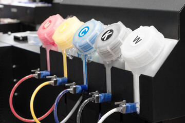 A row of ink cartridges are displayed on a shelf. The cartridges are in various colors, including...