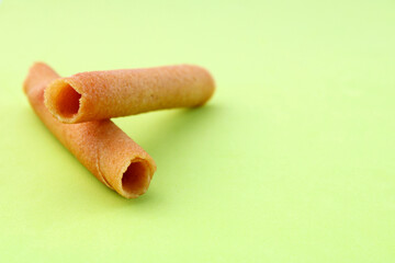 Two sweet cylindrical wafers on green background