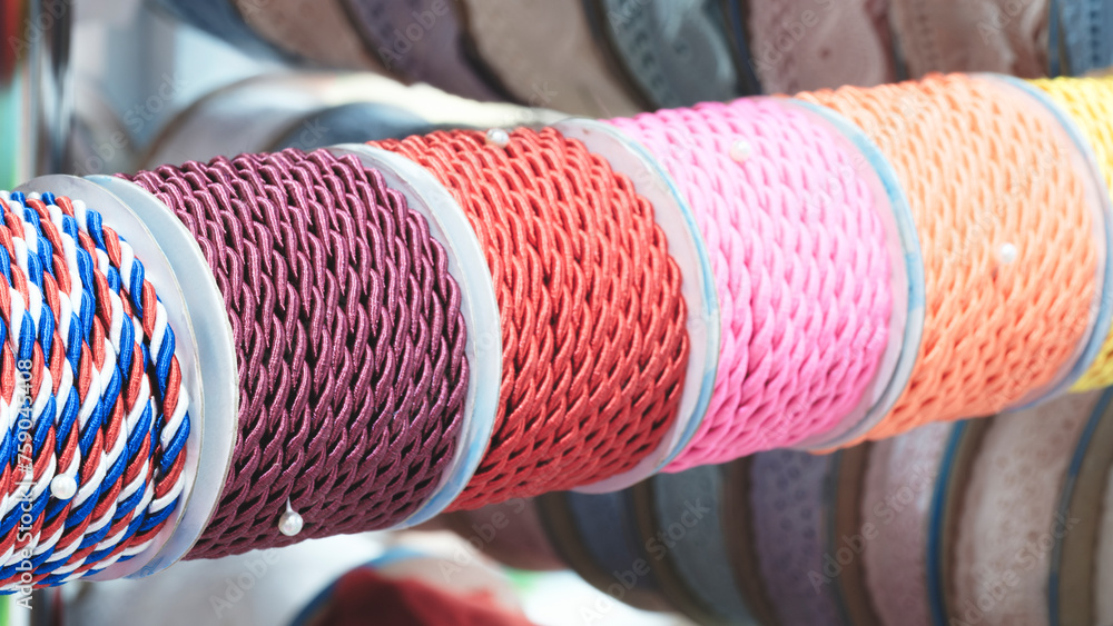 Aufkleber a row of colorful spools of thread, tape, braid are displayed in a store. the spools are arranged in