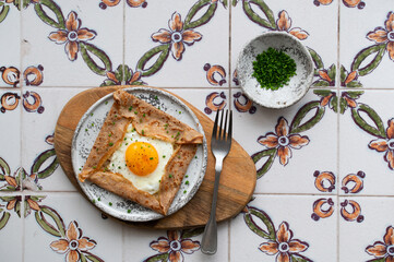 Homemade buckwheat crepes. Galettes bretonnes with cheese and fried egg on a gray background....