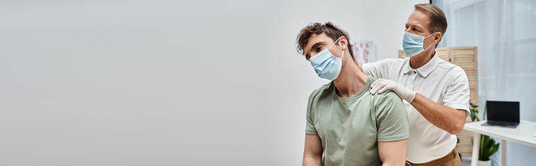 attractive mature doctor with mask helping his patient to rehabilitate in hospital ward, banner - obrazy, fototapety, plakaty
