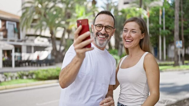 Confident father and smiling daughter enjoy a lovely video call together on the city street, radiating positive vibes and happiness with their casual lifestyle.