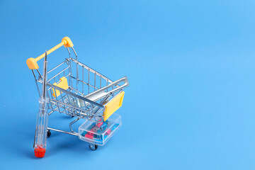 Small shopping cart with set of construction tools on light blue background. Space for text