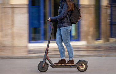 Woman pushing e-scooter in the city,  Ecological transport. Sweeping motion.