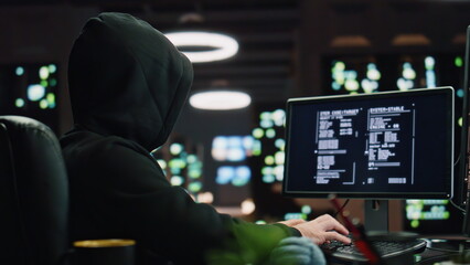Hooded hacker breaking data servers at night closeup. Masked man pointing finger