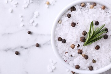 Salt with rosemary and peppercorns in bowl on white marble table, flat lay. Space for text
