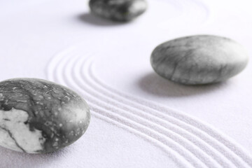 Fototapeta na wymiar Zen concept. Stones and pattern on white sand, closeup