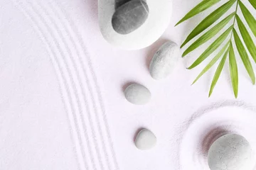 Fototapeten Zen garden stones and green leaves on white sand with pattern, flat lay. Space for text © New Africa