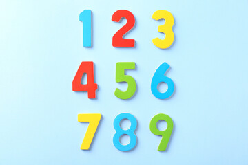 Colorful numbers on light blue background, flat lay