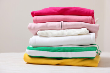 Stack of folded clothes on table against beige background