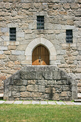 Fototapeta na wymiar Eingang mit einer zweiflügligen, alten Holztür zu einer alten Burg oder Schloss, drei kleine Fenster, Backsteinwand