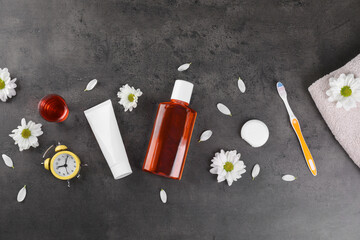 Fresh mouthwash and other oral care products on dark textured table, flat lay