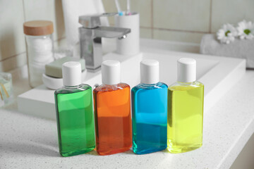 Fresh mouthwashes in bottles on countertop near sink, closeup
