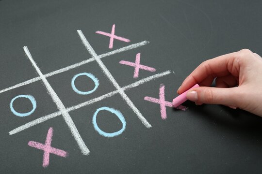 Woman playing tic tac toe on chalkboard, closeup
