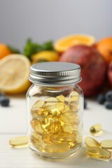 Vitamin pills in bottle and fresh fruits on white wooden table, closeup