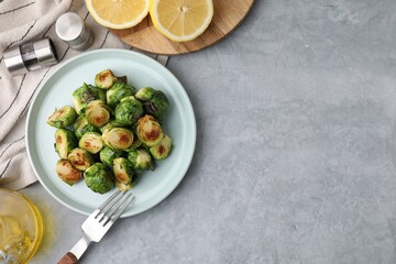 Delicious roasted Brussels sprouts served on grey table, top view. Space for text