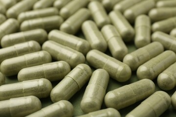 Many vitamin capsules on olive background, closeup