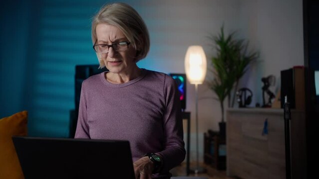 Upset depressed mature middle aged woman in panic holding head in hands in front of laptop frustrated by bad news, online problem or being fired by email feeling desperate shocked exhausted concept