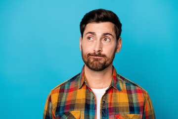 Portrait of intelligent guy with stubble wear checkered shirt thoughtfully look at offer empty space isolated on blue color background