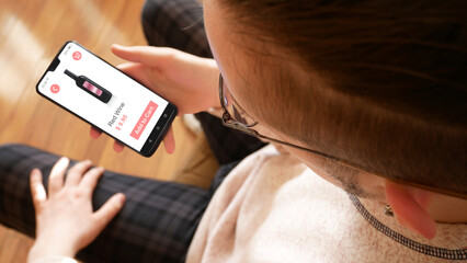 A young man buying a bottle of red wine in an online grocery store