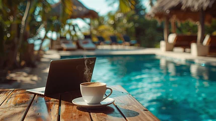 Papier Peint photo Lavable Spa Photo of laptop and cup of coffee standing on table with swimming pool on the background. The concept of remote work and combining leisure with work