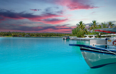 Colourful sunset at the maldive island with a boat and boardwalk