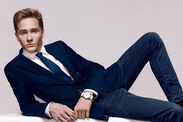 Elegant young handsome man with a wristwatch. Fashion portrait studio.