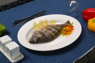 fried fish with fresh herbs and lemon restaurant blue table 
