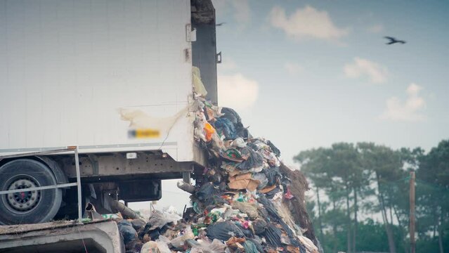 Long shot of a semi-trailer unloads garbage at landfill site.