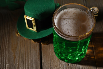 St. Patrick's day party. Green beer, leprechaun hat and gold on wooden table, closeup. Space for...