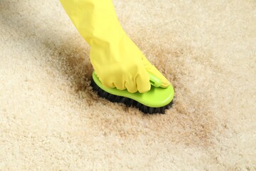 Woman removing stain from beige carpet, closeup