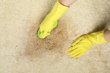 Woman removing stain from beige carpet, top view