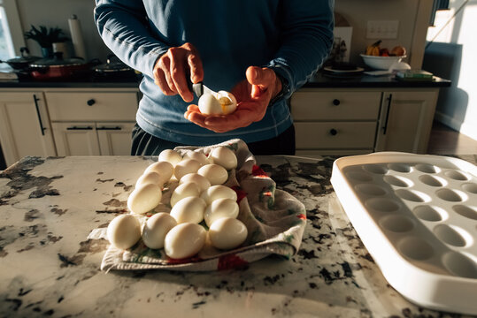 Boiled eggs being cut in half with a knife. 