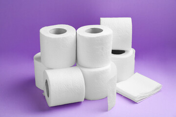 Soft toilet paper rolls on violet background