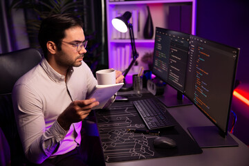 Smart IT developer working with coffee on software development coding on pc screen, reading note...