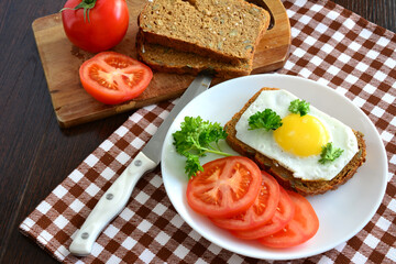 sandwich with fried egg and wholegrain bread decorated with parsley and tomato
