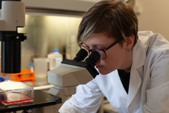 woman scientist looking at the microscope in a laboratory, research