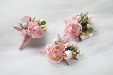 Wedding stuff. Stylish boutonnieres on white veil, closeup