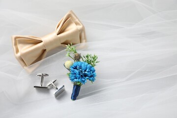 Wedding stuff. Stylish boutonniere, bow tie and cufflinks on white veil, space for text