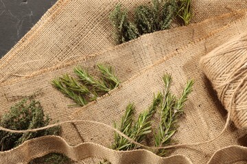 Natural burlap fabric, jute and fresh herbs on table, top view