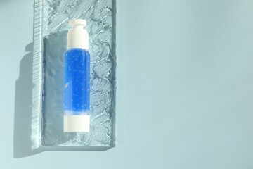 Bottle of cosmetic product on light blue background, top view. Space for text