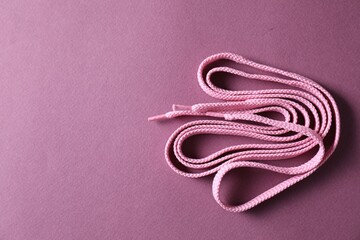 Naklejka premium Stylish pink shoe laces on violet background, top view. Space for text