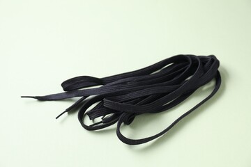 Stylish black shoe laces on light olive background