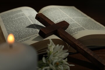 Cross, Bible, flowers and church candle on wooden table