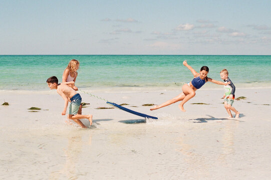 Kids playing with a boogie board at the beach