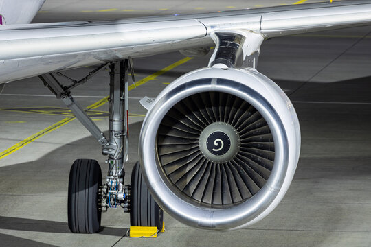 Closeup of jet engine and main gear of an Airbus A320. Airplane parked at night at the apron.