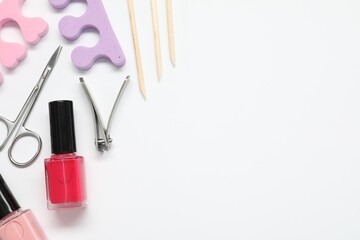 Nail polishes and set of pedicure tools on white background, flat lay. Space for text