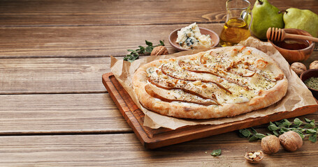 Flatbread pizza with pears, blue cheese and walnut on wooden background with ingredients for...